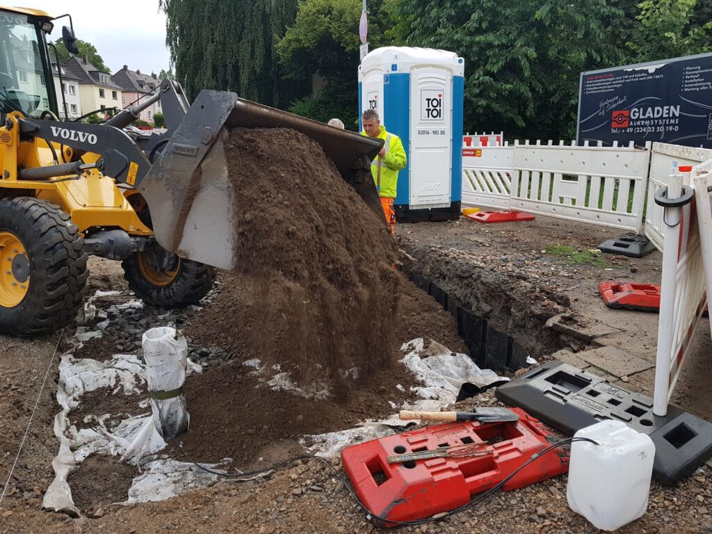 Schaufellader füllt Baugrube mit Rigolenkörper mit Substrat auf