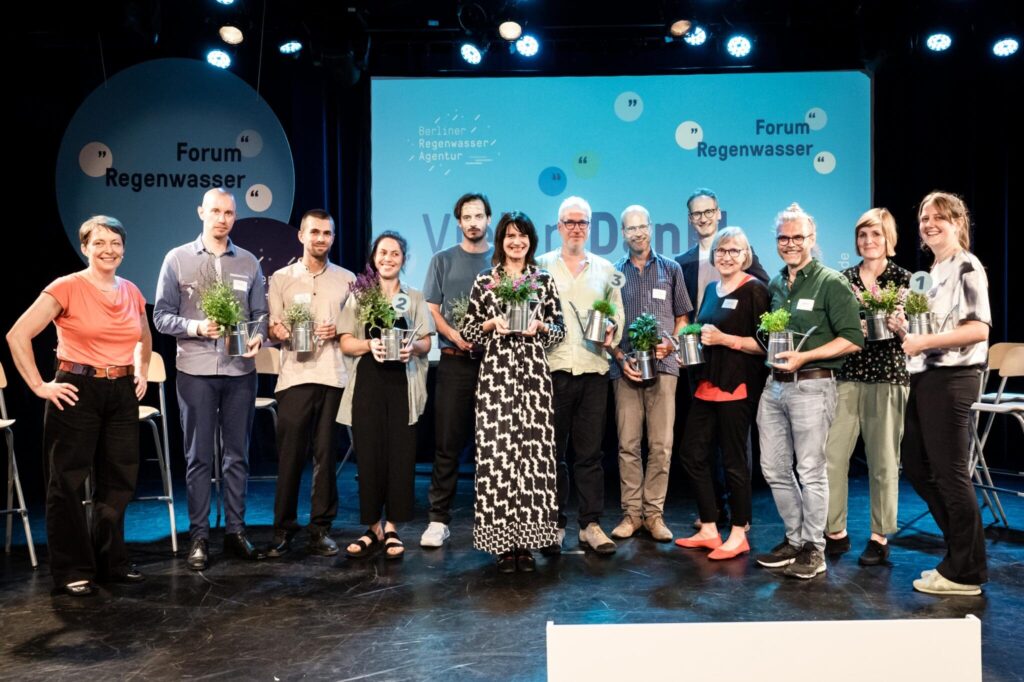 die 10 Ideengeber:innen mit Staatssekretärin Britta behrendt und den Moderatoren der Veranstaltung Darla Nickel und Wolfram Schroff auf der Bühne