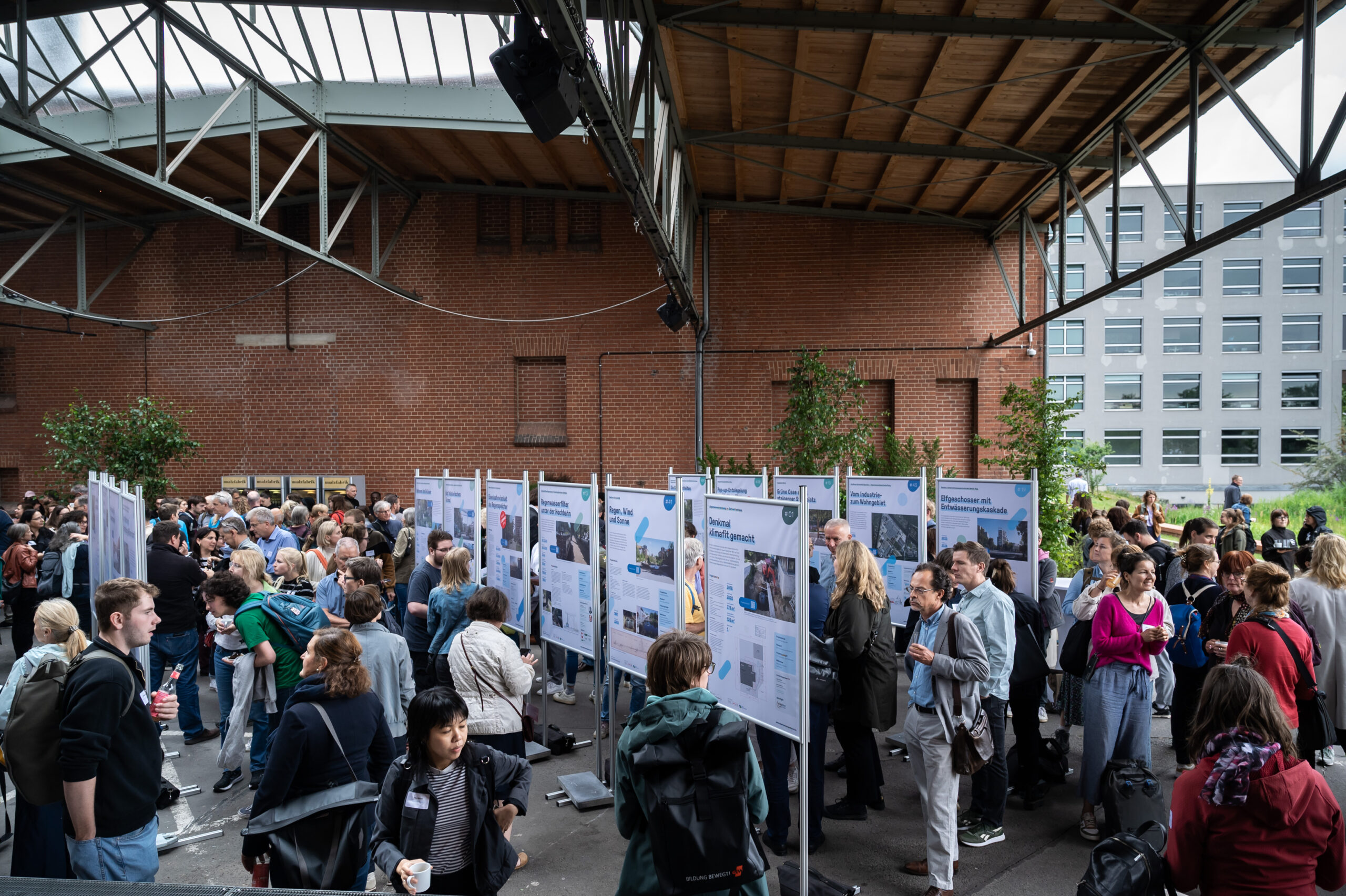 Teilnehmende des Forums sehen sich die Plakatausstellung an