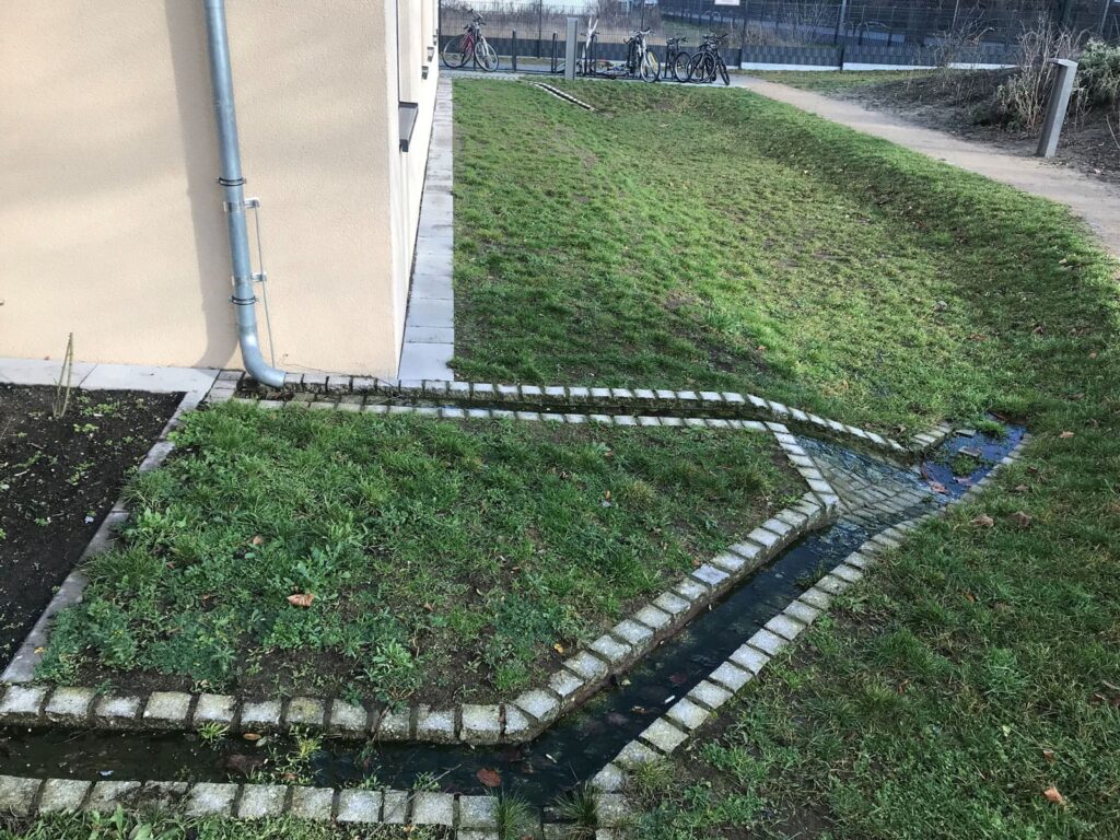 Einlauf vom Regenfallrohr in eine Rasenmulde