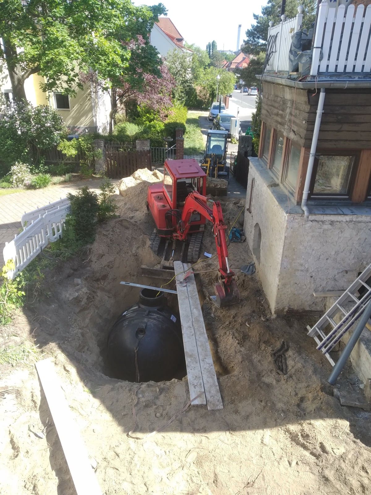 Beengte Verhältnisse beim Einbau der Regenwasserzisterne und -versickerung Auf dem Bild ist ein Bagger zu sehen, der die Baugrube für Zisterne und Rigole aushebt