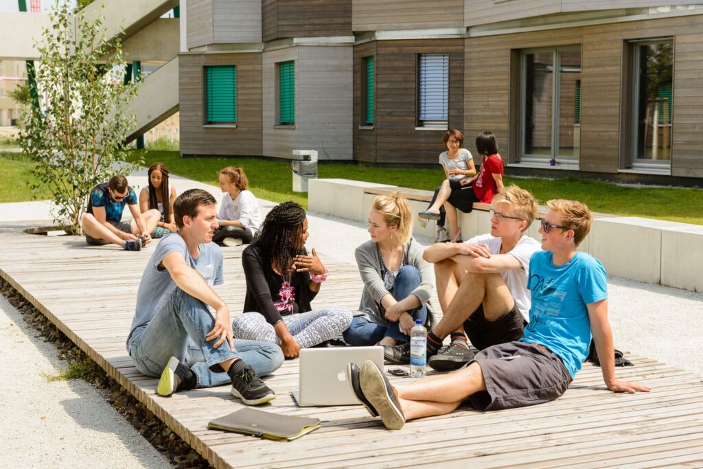 Studierende die sich auf den Sitzmöglichkeiten der Außenanlage unterhalten