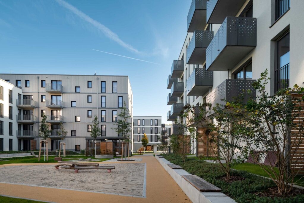 Der Innenhof - ein grüner Rückzugsort im Quartier. Er lädt zum Entspannen ein und bietet Raum für Spiel und Kreativität. Innovative Entwässerungslösungen leiten das Regenwasser direkt über die Balkone in die Pflanzfläche, wo es versickert.