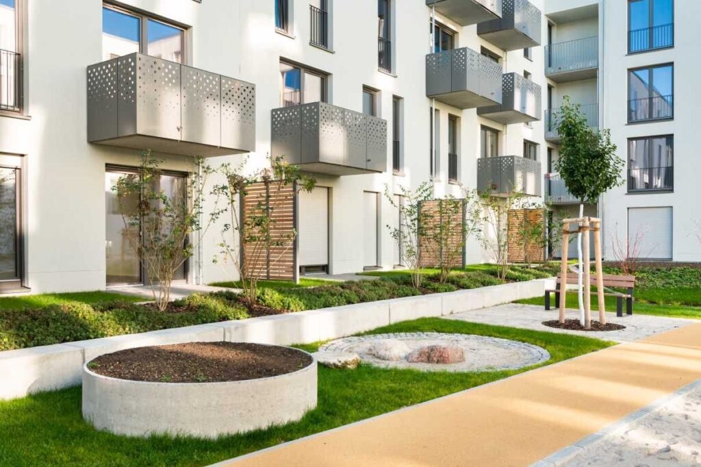 Nachhaltige Regenwassernutzung im Quartier: Regenwasser fließt in die Grünflächen und Staudenbeete, wo es versickert und gemeinsam mit den Pflanzen zur Kühlung und Aufwertung des Quartiers beiträgt.