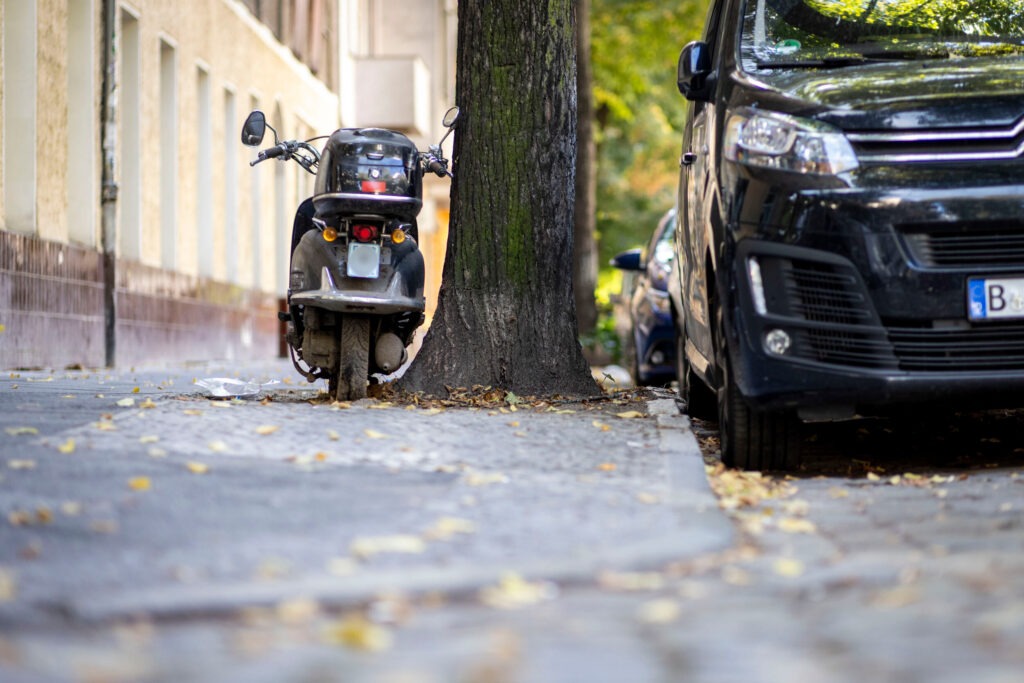 kleine Baumscheibe umstellt mit Auto und Motorrad