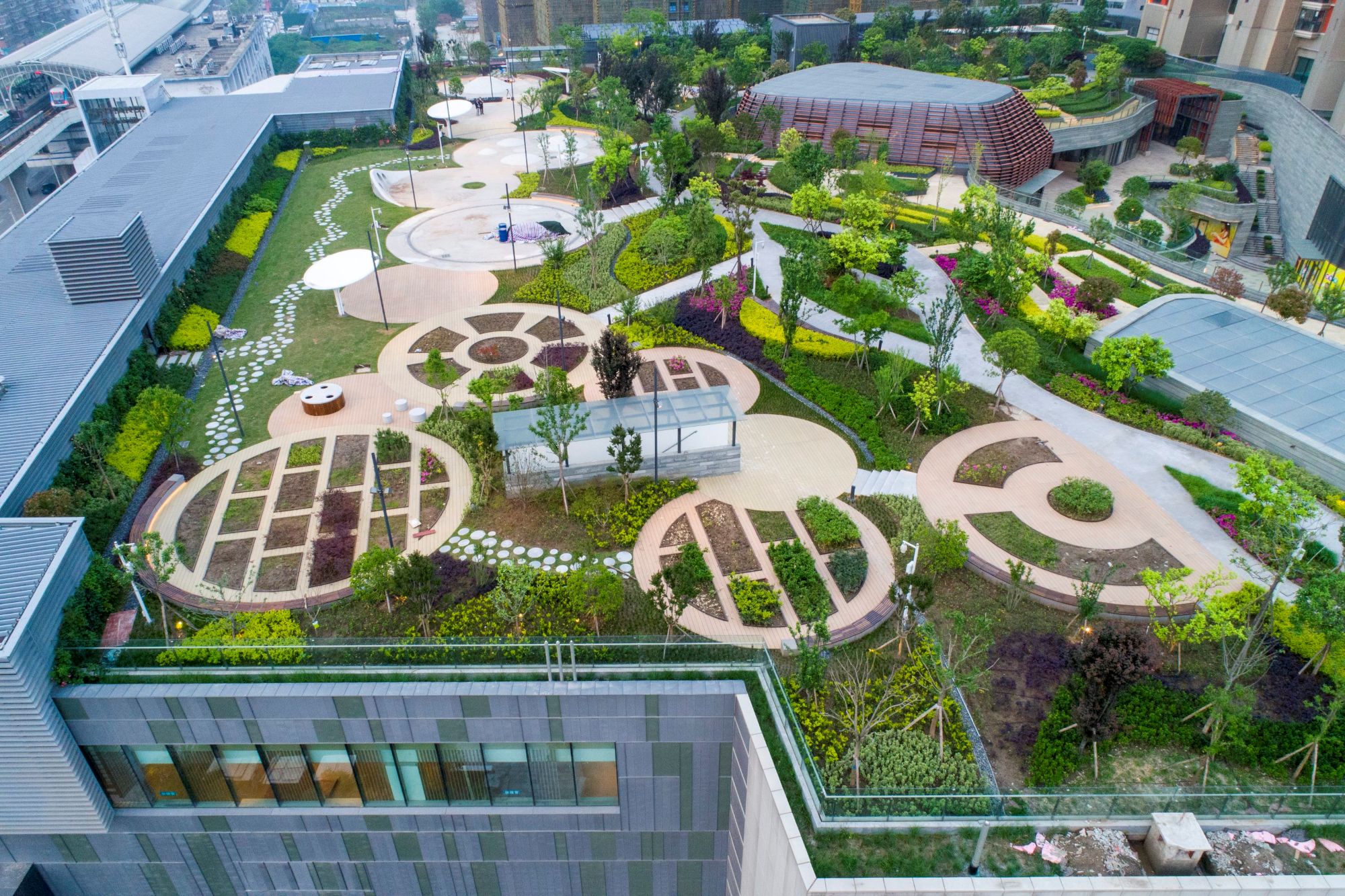Spielplätze, Spazierwege und Sitzgelegenheiten auf dem Dachpark des Einkaufzentrums in Wuhan. Die intensive Bepflanzung schafft ein angenehmes Mikroklima und fördert die Biodiversität - ein Schwammstadt-Beispiel.