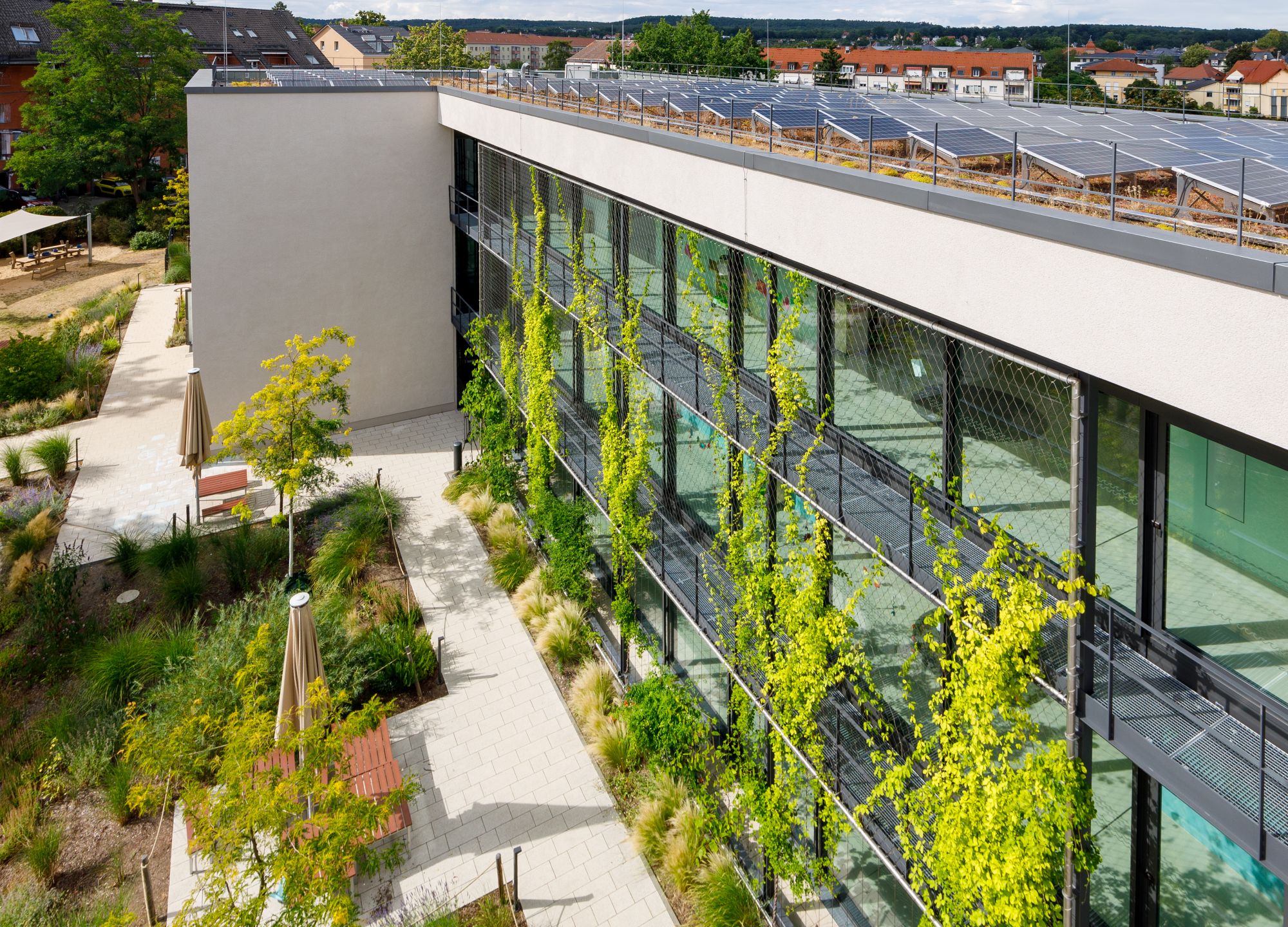 Gebäude in einem wassersensiblen Quartier mit entsiegelten Flächen und Dach- und Fassadenbegrünung
