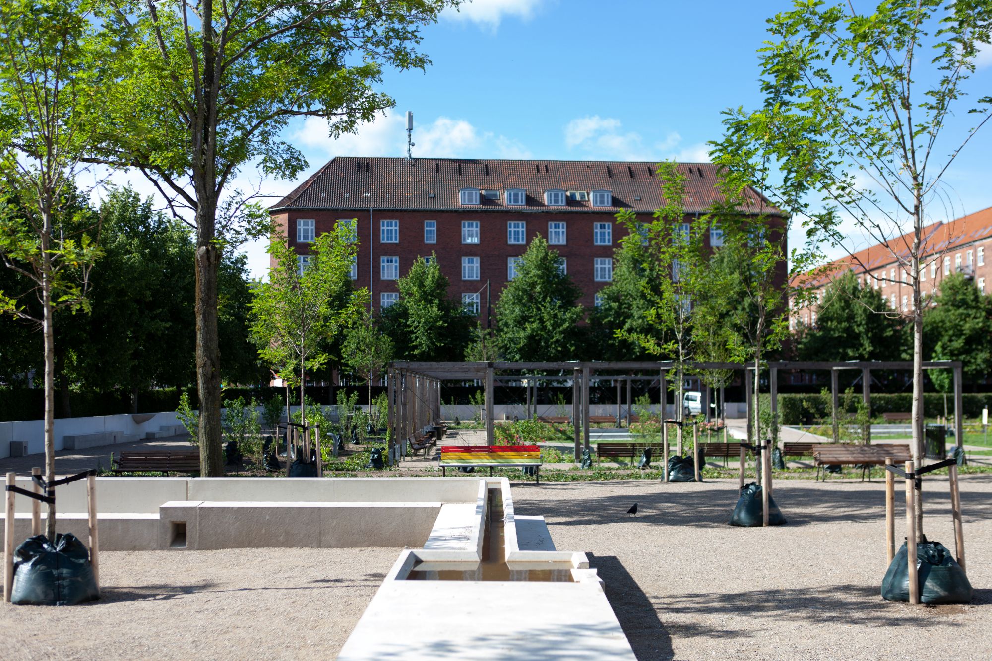 Um und durch den Park führt eine Betonmauer mit multifunktionalem Design: Die „längste Sitzbank Kopenhagens“, in die offene Wasserkanäle eingelassen sind, ist im Alltag Spiel- und Verweilort. Bei Starkregen dient sie dazu, Oberflächenwasser im Park zu halten.