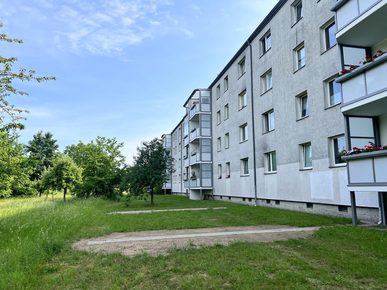 Projektgebiet Ellernweg kurz nach Herstellung der Muldenrinnen. Ansicht auf Hausfassade, Muldenrinnen und Grünfläche.